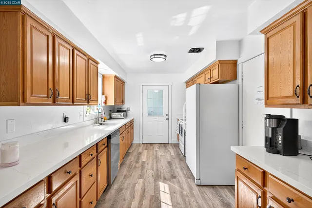a view of a kitchen with refrigerator and wooden floor