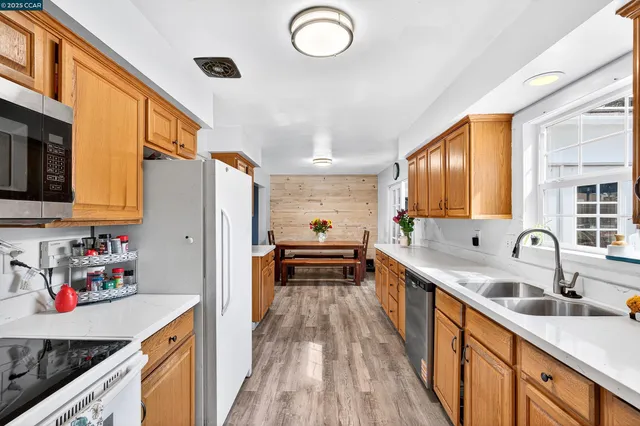 a large kitchen with stainless steel appliances granite countertop a stove a sink dishwasher and a dining table with wooden floor