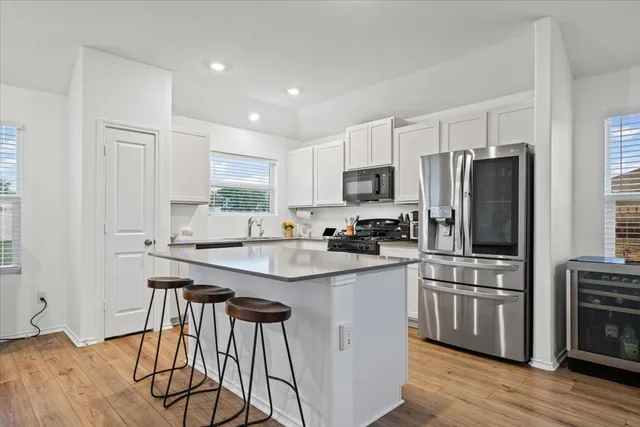 a kitchen with stainless steel appliances a sink a stove a refrigerator cabinets and a dining table