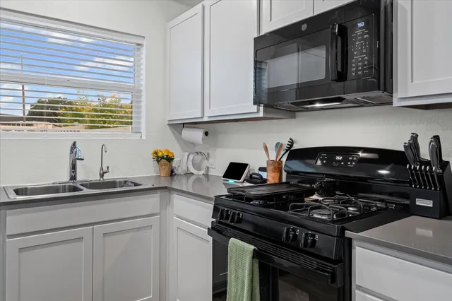 a kitchen with stainless steel appliances granite countertop white cabinets and a stove top oven