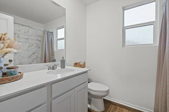 a bathroom with a toilet sink vanity and mirror