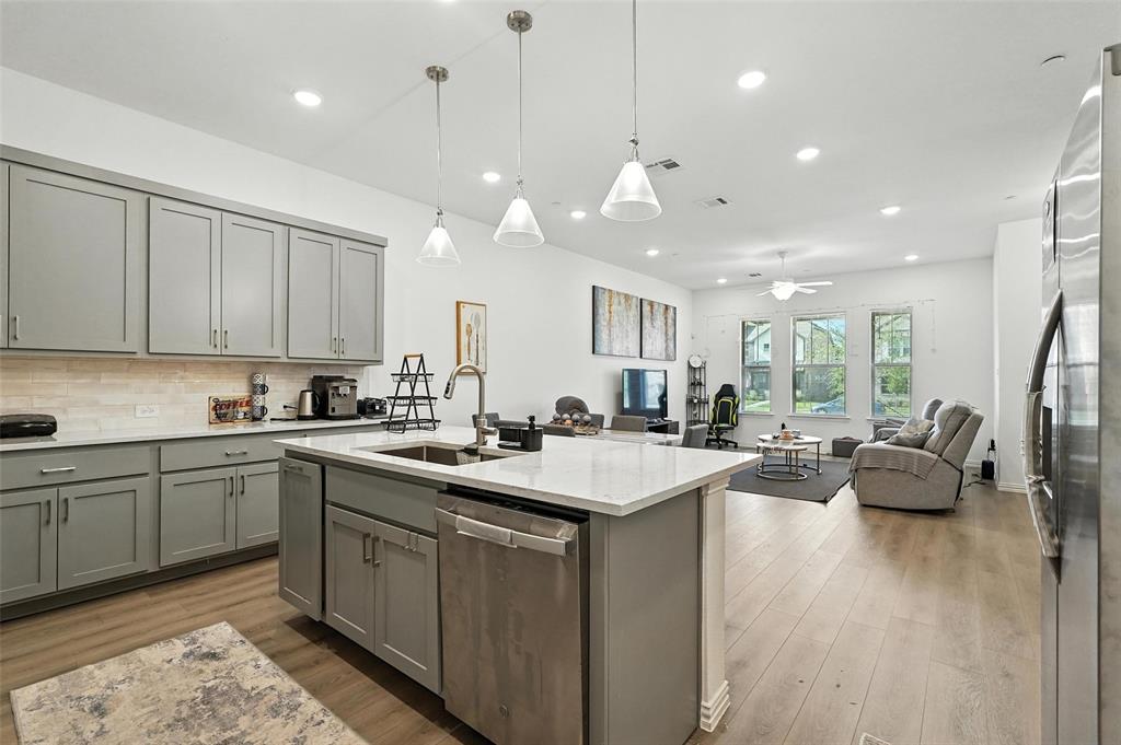 6535 Baritone Court Sachse, TX 75048 - Photo 22 of 24 a kitchen with stainless steel appliances granite countertop sink stove and white cabinets with wooden floor