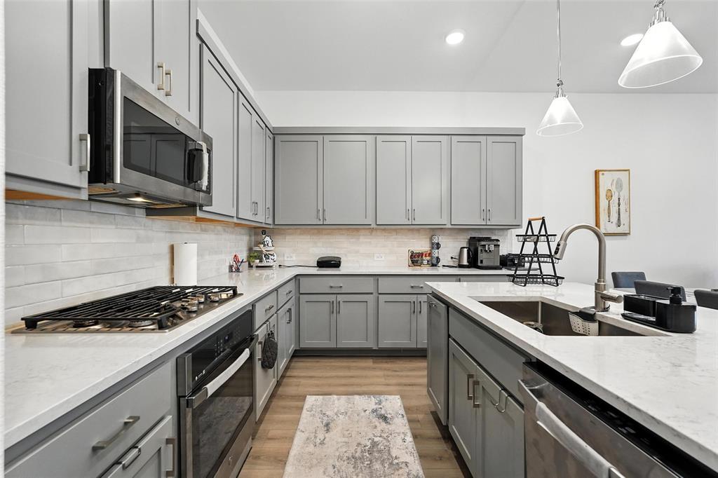 6535 Baritone Court Sachse, TX 75048 - Photo 8 of 24 a kitchen with stainless steel appliances granite countertop a sink a stove top oven a counter space and cabinets