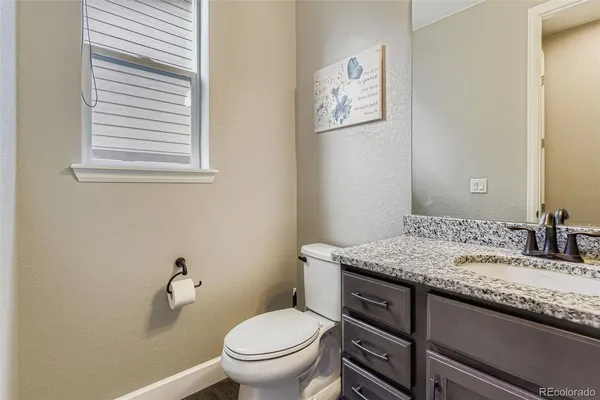 a bathroom with a granite countertop toilet sink and mirror