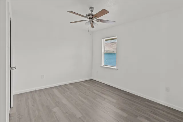 an empty room with wooden floor and ceiling fan