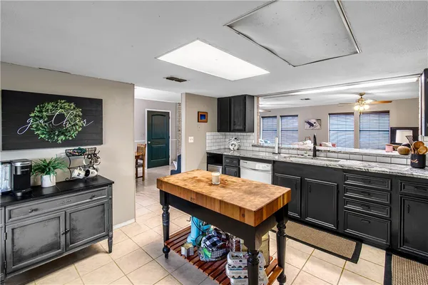 a kitchen with granite countertop a table chairs sink and stove