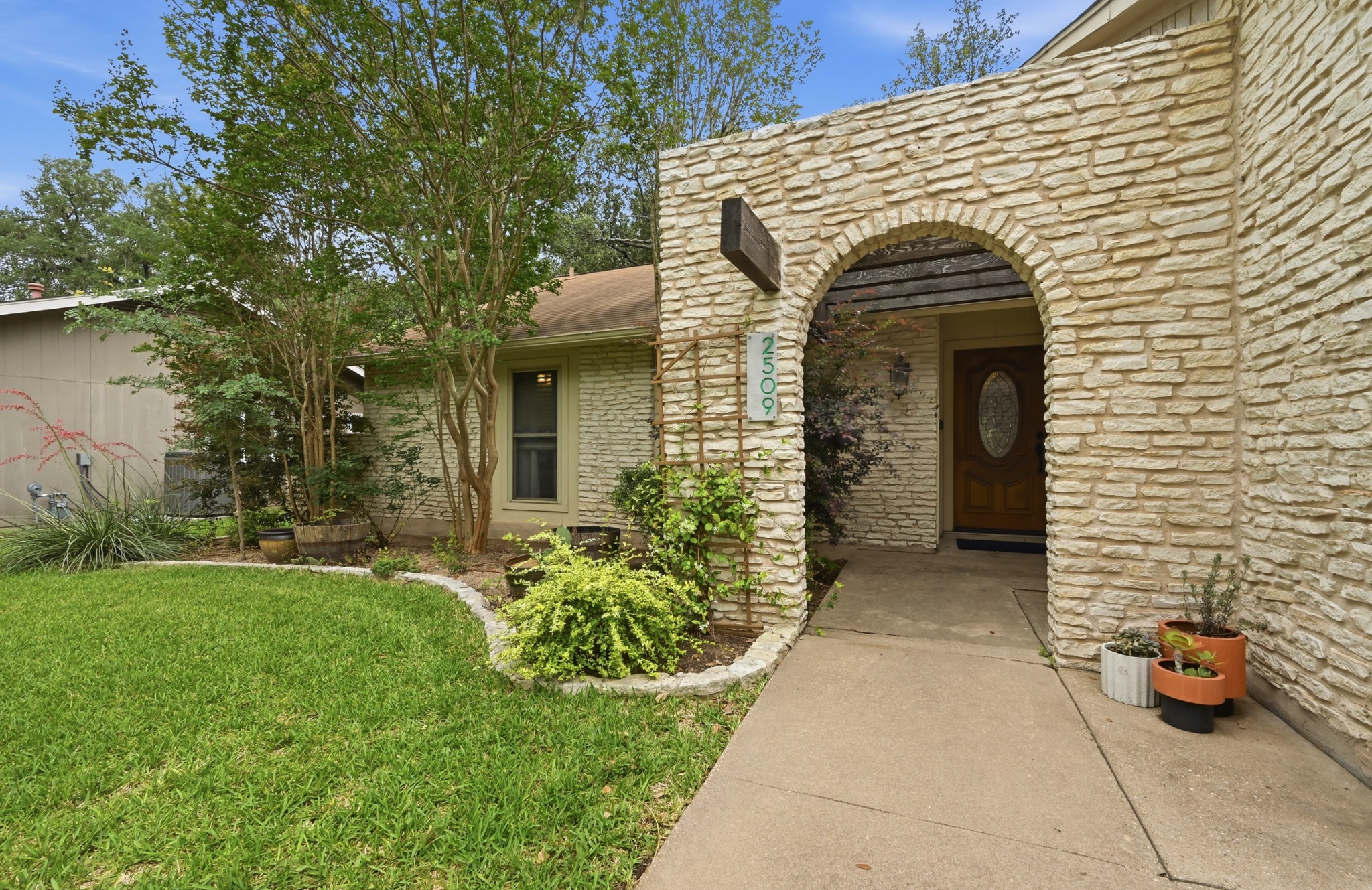 2509 Redleaf Lane Austin, TX 78745 - Photo 27 of 28 Stone facade entry arch with a recessed wooden front door featuring an oval glass insert