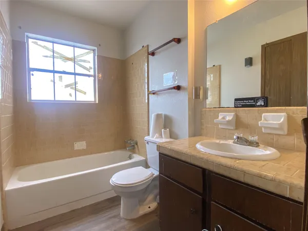 a bathroom with a granite countertop sink toilet a mirror and bathtub