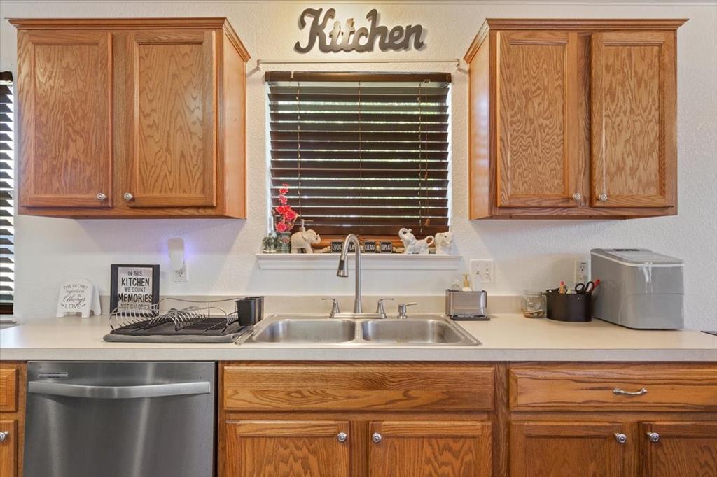 10817 Lilry Road Waco, TX 76708 - Photo 15 of 27 Kitchen with stainless steel dishwasher, light countertops, wood finish cabinets, and a textured wall