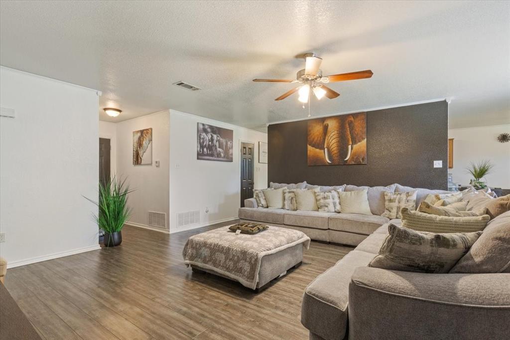 10817 Lilry Road Waco, TX 76708 - Photo 6 of 27 Living room featuring a ceiling fan, wood finished floors, and a textured ceiling