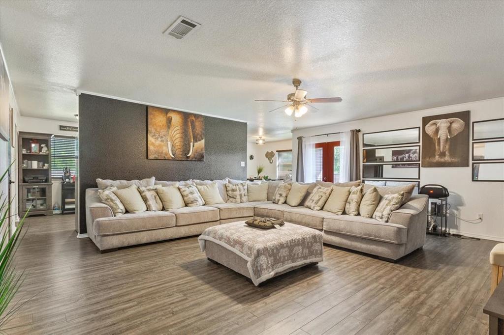 10817 Lilry Road Waco, TX 76708 - Photo 9 of 27 Living room with ceiling fan, a textured ceiling, dark wood-style flooring, and healthy amount of natural light