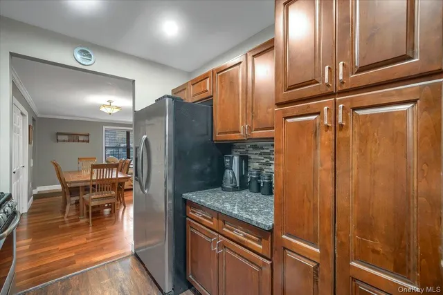 a kitchen with granite countertop a refrigerator a stove and a dining table with wooden floor