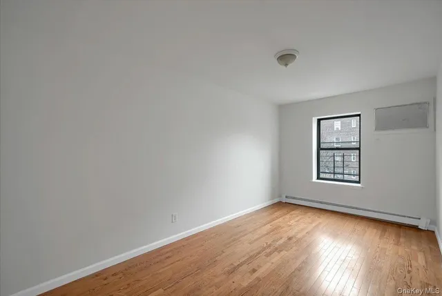 a view of an empty room with wooden floor and window