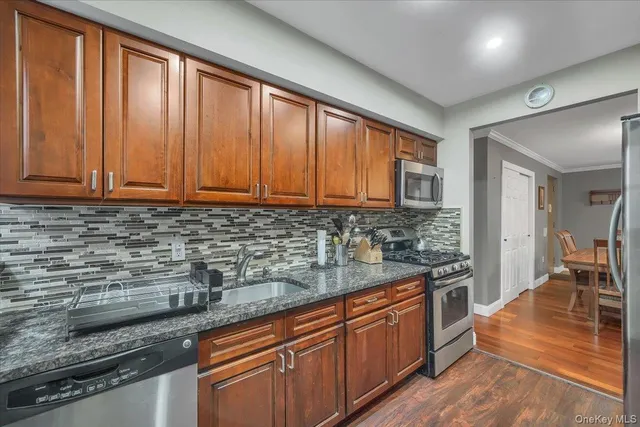 a kitchen with stainless steel appliances granite countertop wooden cabinets a sink and dishwasher a stove top oven with wooden floor