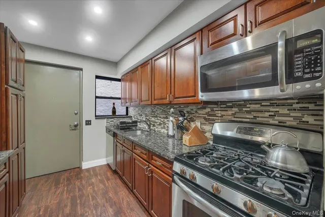 a kitchen with stainless steel appliances granite countertop a stove a sink and a microwave
