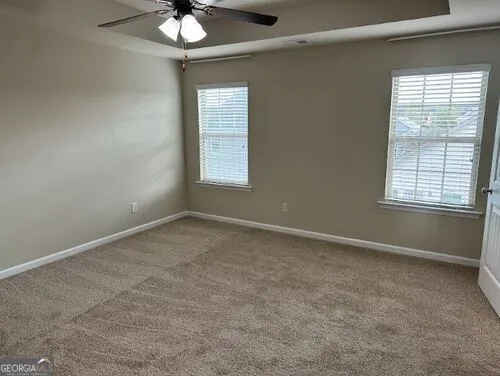 an empty room with a chandelier fan and windows