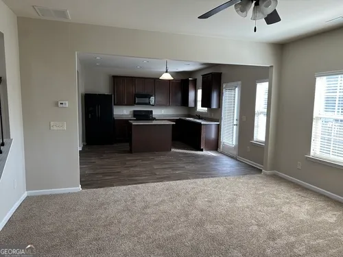 a living room with stainless steel appliances kitchen island granite countertop a refrigerator stove and sink