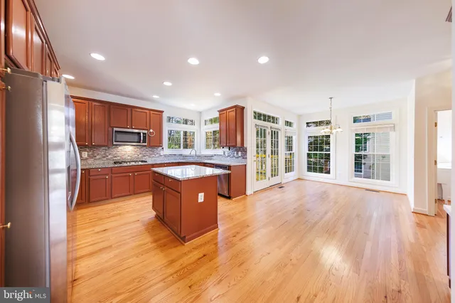 a large kitchen with stainless steel appliances granite countertop a large counter top a sink a stove a refrigerator and cabinets