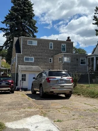 a front view of a house with cars parked on road