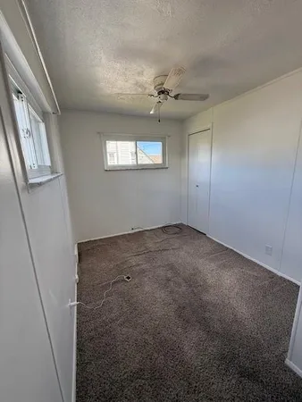 an empty room with windows and fan