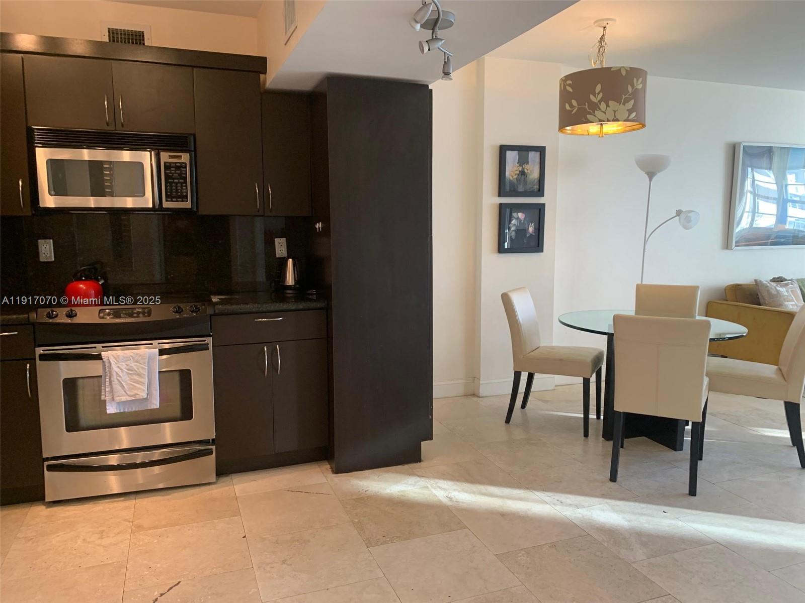 100 Lincoln Road, Unit 1122 Miami Beach, FL 33139 - Photo 11 of 29 a kitchen with stainless steel appliances kitchen island granite countertop a refrigerator and a stove top oven