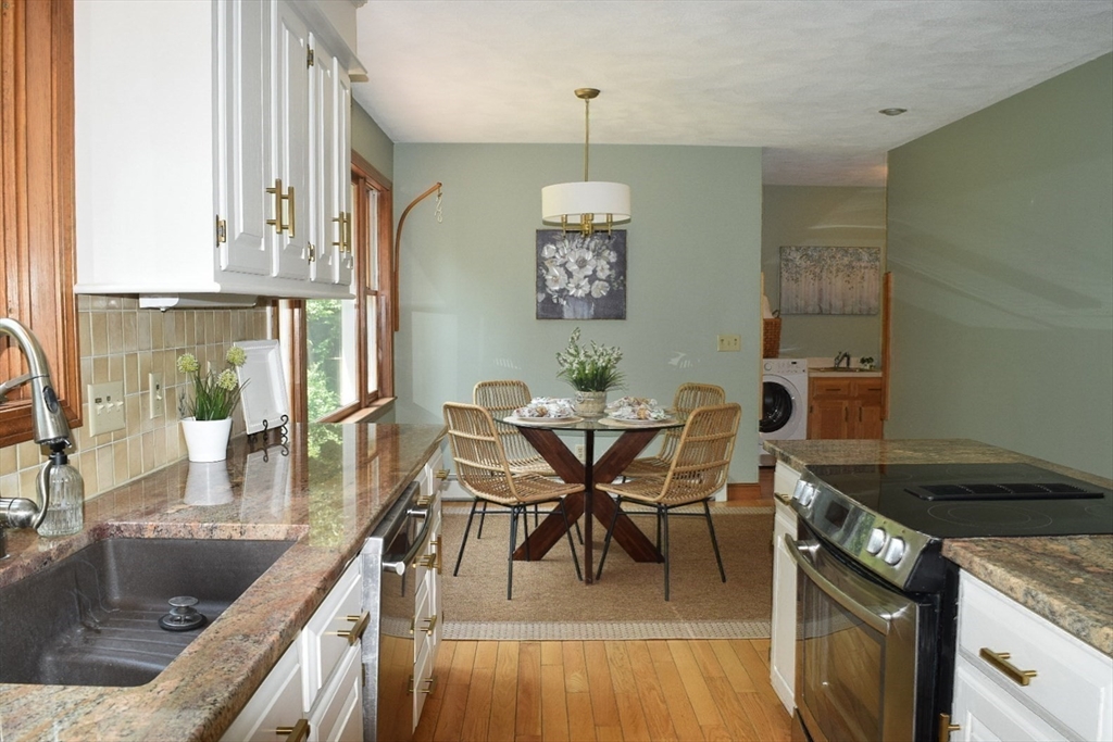 111 Bear Hill Road North Andover, MA 01845 - Photo 10 of 41 a kitchen with stainless steel appliances granite countertop a stove top oven a dining table and chairs with wooden floor