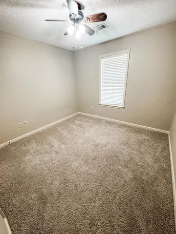an empty room with a window and a ceiling fan