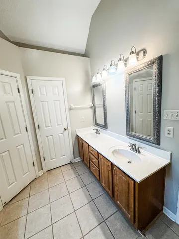 a bathroom with a double vanity sink mirror and bathtub