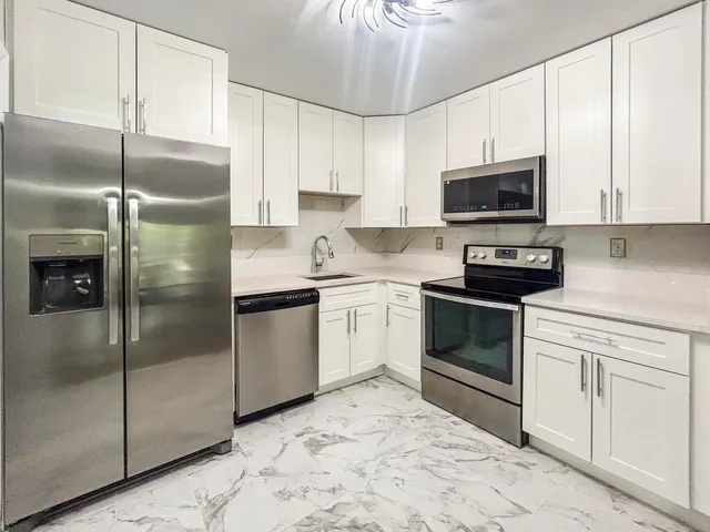 a kitchen with a refrigerator stove and white cabinets