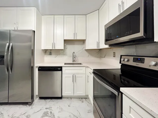 a kitchen with stainless steel appliances granite countertop a refrigerator stove top oven and sink