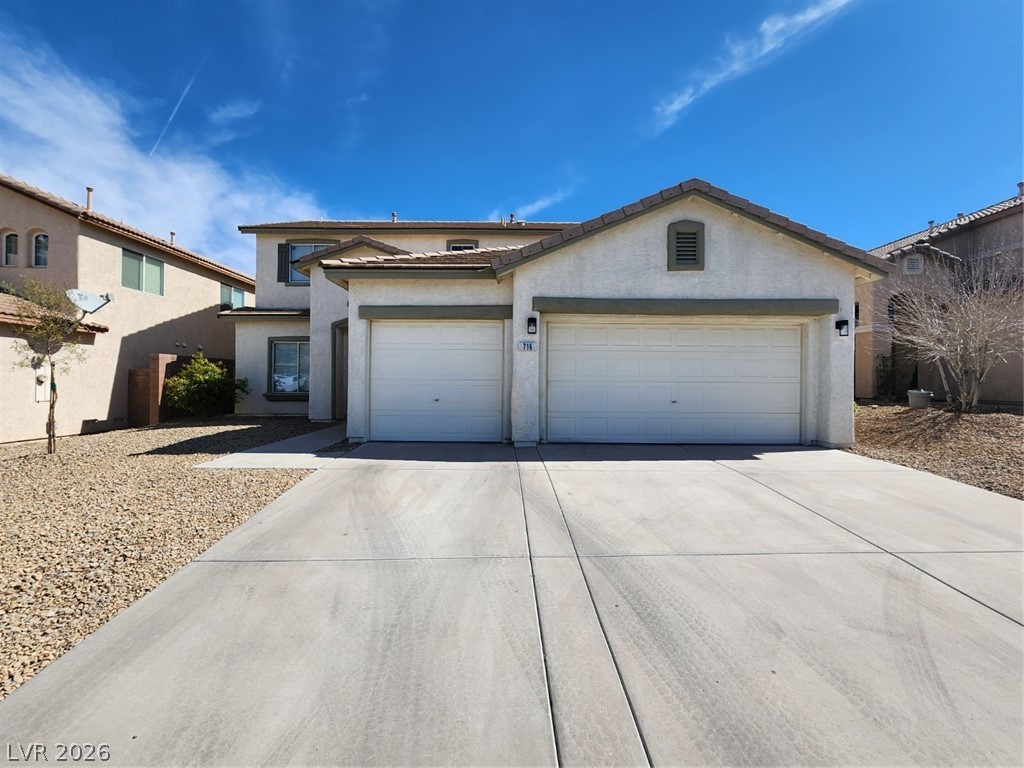 View of front of home with concrete driveway, a garage, stucco siding, and a tile roof