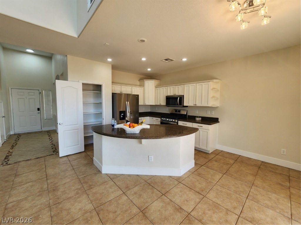 716 Sharon Hills Street Henderson, NV 89052 - Photo 12 of 66 Kitchen with open shelves, stainless steel appliances, light tile patterned floors, white cabinetry, and a center island