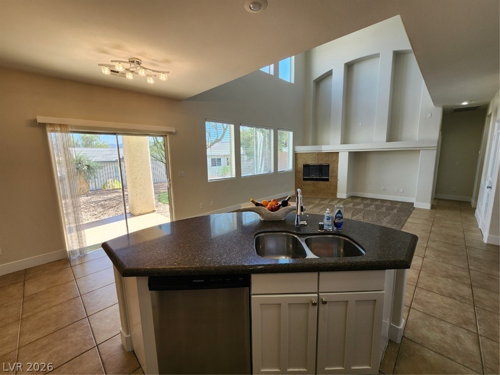 716 Sharon Hills Street Henderson, NV 89052 - Photo 64 of 66 Kitchen featuring dishwasher, a center island with sink, a tile fireplace, open floor plan, and light tile patterned floors