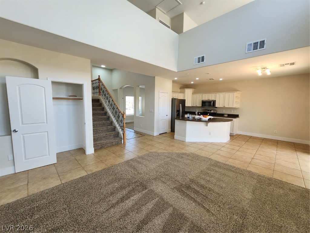 716 Sharon Hills Street Henderson, NV 89052 - Photo 66 of 66 Kitchen featuring light tile patterned flooring, a kitchen island with sink, arched walkways, white cabinets, and open floor plan