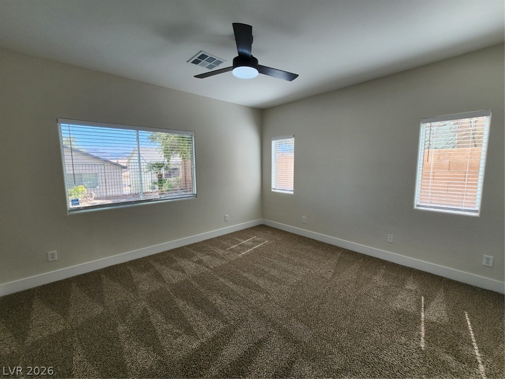 716 Sharon Hills Street Henderson, NV 89052 - Photo 13 of 66 Empty room featuring dark colored carpet, plenty of natural light, and ceiling fan