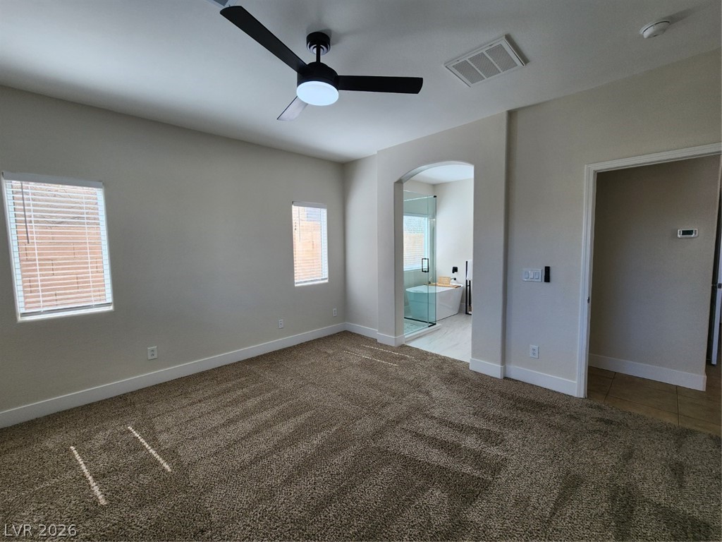 716 Sharon Hills Street Henderson, NV 89052 - Photo 14 of 66 Unfurnished bedroom featuring dark carpet, ceiling fan, arched walkways, and ensuite bathroom