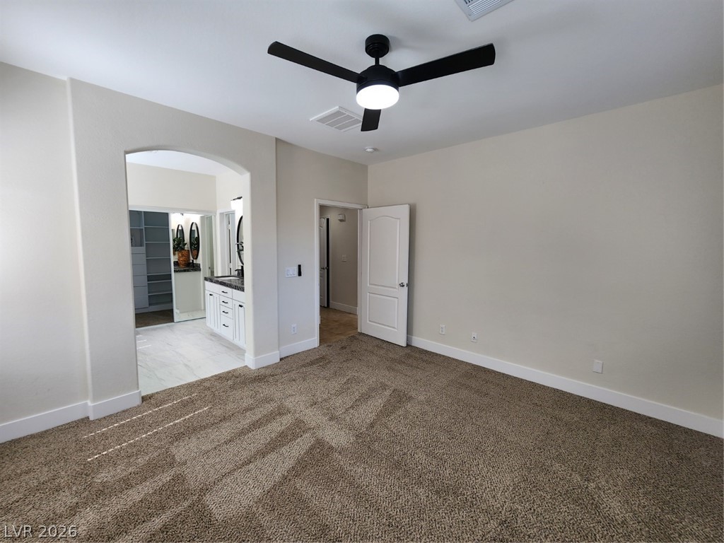 716 Sharon Hills Street Henderson, NV 89052 - Photo 15 of 66 Unfurnished bedroom featuring arched walkways, light colored carpet, ensuite bath, and a ceiling fan