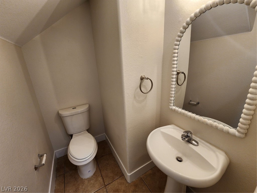 716 Sharon Hills Street Henderson, NV 89052 - Photo 26 of 66 Half bath with tile patterned flooring, a textured wall, and lofted ceiling