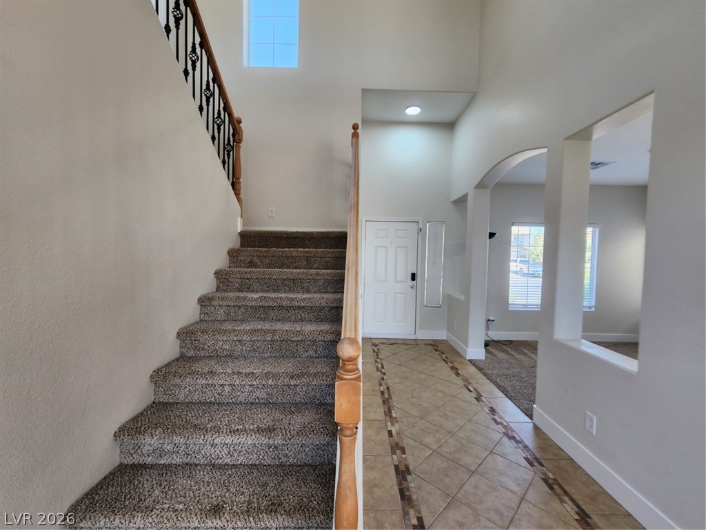 716 Sharon Hills Street Henderson, NV 89052 - Photo 28 of 66 Stairway with a high ceiling, arched walkways, inlaid floor details, recessed lighting, and tile patterned floors