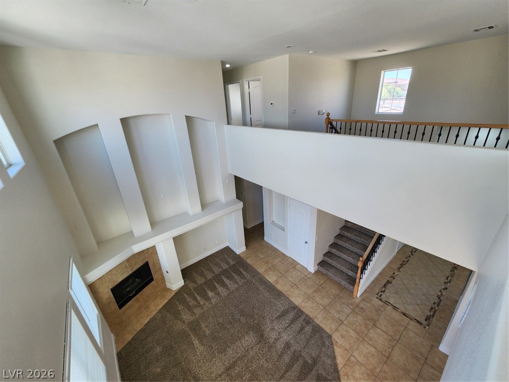 716 Sharon Hills Street Henderson, NV 89052 - Photo 40 of 66 Staircase with built in features, a tiled fireplace, and a high ceiling