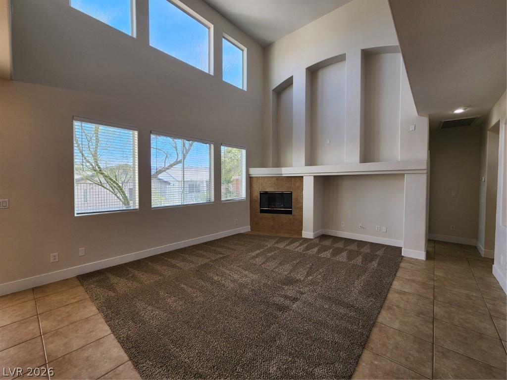 716 Sharon Hills Street Henderson, NV 89052 - Photo 7 of 66 Unfurnished living room featuring a high ceiling, light tile patterned floors, and a fireplace