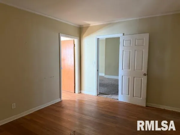 an empty room with wooden floor and closet area