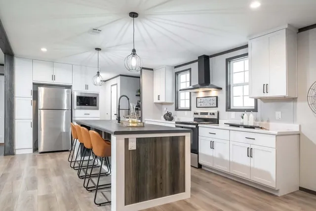 a kitchen with stainless steel appliances a sink a stove a refrigerator cabinets and a center island