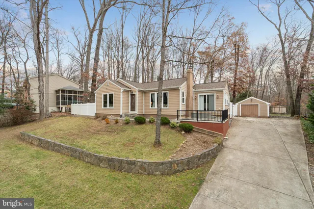 a view of a white house with a small yard and large tree