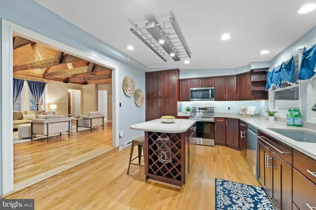 a kitchen with stainless steel appliances kitchen island granite countertop a table chairs in it and wooden floors