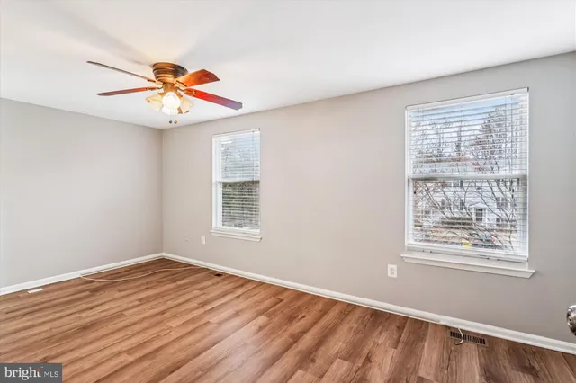 a view of an empty room with window and wooden floor