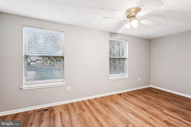 a view of an empty room with a window and a ceiling fan