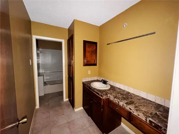 a bathroom with a granite countertop bathtub shower sink vanity and toilet