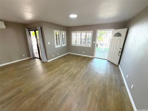 an empty room with wooden floor and windows