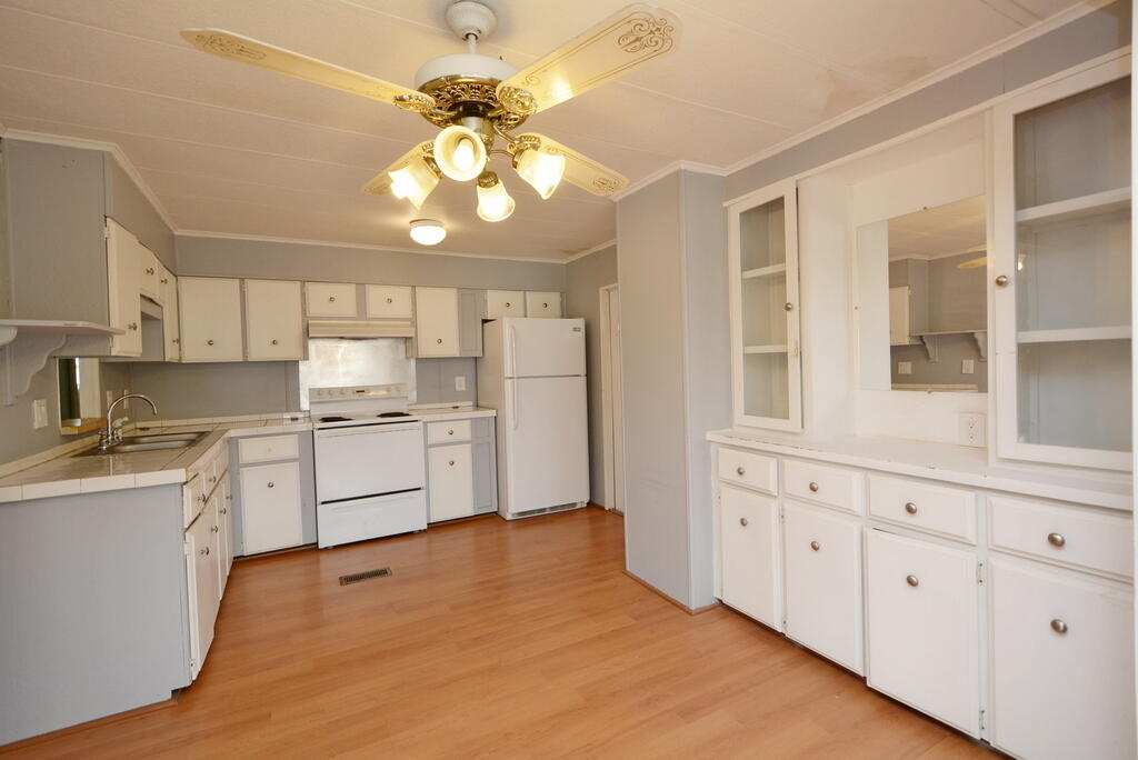 623 Periwinkle Circle Barefoot Bay, FL 32976 - Photo 13 of 37 a kitchen with white cabinets and stainless steel appliances